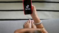 Une jeune fille tient son smartphone, sur lequel apparaît le logo du réseau social Tik Tok, le 7 juillet 2026 à Bruxelles 