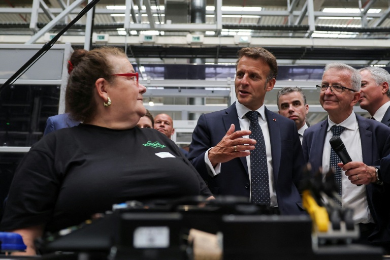 Le président Emmanuel Macron (d) parle avec une employé elors de sa visite de l'usine Vorwerk, dans le cadre du sommet 