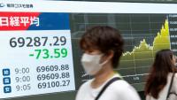 Un passant devant un panneau d'affichage électronique indiquant l'indice Nikkei à la Bourse de Tokyo, dans une rue de Tokyo, le 29 juin 2026.