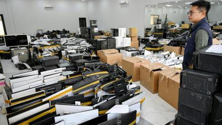 Un policier à côté de matériel saisi dans des centres d’opérations de cyberarnaques, au commissariat de la police municipale de Phnom Penh, le 11 mars 2026 au Cambodge