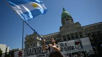 Un manifestant brandit le drapeau national argentin lors d'une manifestation devant le Parlement où est examinée la réforme du travail du président Javier Milei, à Buenos Aires, le 27 février 2026