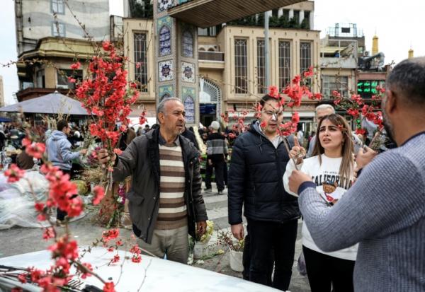 Une Iranienne achète des fleurs sur le bazar Tajrish au nord de Téhéran, le 19 mars 2026, à la veille de Norouz, le nouvel an persan