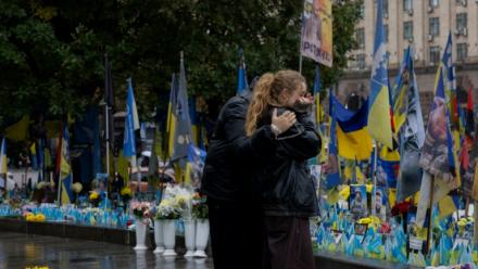 Des passants devant un mémorial improvisé pour les soldats ukrainiens et étrangers morts au combat, à Kiev le 7 octobre 2025