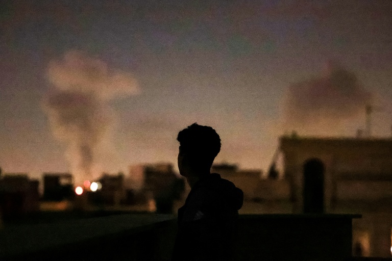 Une personne regarde la fumée de frappes aériennes sur Téhéran, le 4 mars 2026 en Iran