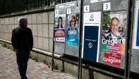Une personne passe devant des affiches électorales pour les municipales, le 18 mars 2026 à Paris