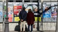 Des passants regardent les affiches électorales des candidats aux municipales à Paris le 9 mars 2026