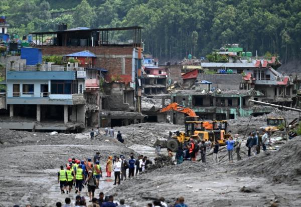 Des pelleteuses dégagent la boue et les décombres après la crue destructrice qui a fait au moins 633 morts à la frontière entre le Népal et la Chine, le 29 août 2026 à Dhunge Bazaar, dans le district népalais de Nuwakot  