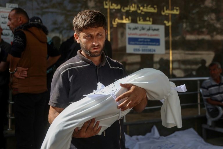 Un Palestinien porte le corps enveloppé d'un enfant tué lors d'une frappe israélienne, à l'hôpital Al-Chifa de la ville de Gaza, le 26 mai 2025