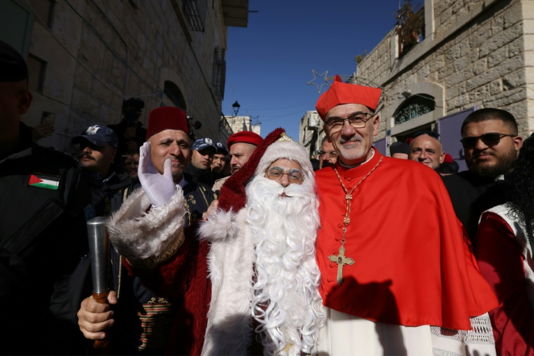 Le patriarche latin de Jérusalem, le cardinal Pierbattista Pizzaballa, pose pour une photo avec un homme habillé en Père Noël avant son arrivée à l'église de la Nativité, à Bethléem, en Cisjordanie occupée, le 24 décembre 2024