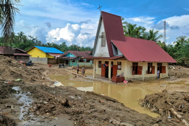 Des villageois se rendent à l'église protestante d'Angkola pour la messe de Noël, dans le village d'Aek Ngadol, le 25 décembre 2025, dans la province de Sumatra touchée par des inondations et glissements de terrain meurtriers, en Indonésie
