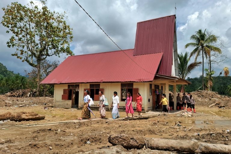 Des villageoisquittent l'église protestante d'Angkola après la messe de Noël, dans le village d'Aek Ngadol, le 25 décembre 2025, dans la province de Sumatra touchée par des inondations et glissements de terrain meurtriers, en Indonésie