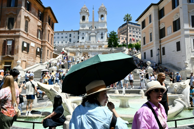 Des touristes se protègent de la chaleur avec des parapluies et des chapeaux, à Rome, le 26 mai 2026