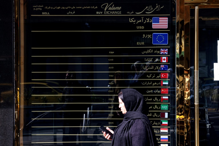 Une Iranienne marche devant un bureau de change, à Téhéran le 22 février 2026