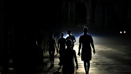 Des habitants marchent dans une rue de La Havane pendant une panne d'électricité, le 13 mai 2026 à Cuba