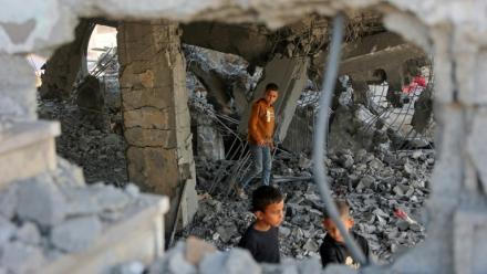 Des garçons marchent parmi les décombres d’un bâtiment endommagé, qui abritait des personnes déplacées dans le quartier de Zeitoun, à Gaza-Ville, le 20 novembre 2025, au lendemain d'une frappe israélienne