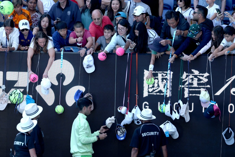 L'Espagnol Carlos Alcaraz (en bas) signe des autographes après avoir battu le Français Corentin Moutet au troisième tour de l'Open d'Australie, à Melbourne, le 23 janvier 2026