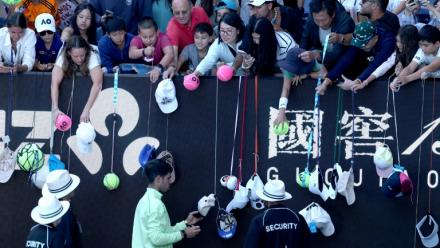 L'Espagnol Carlos Alcaraz (en bas) signe des autographes après avoir battu le Français Corentin Moutet au troisième tour de l'Open d'Australie, à Melbourne, le 23 janvier 2026