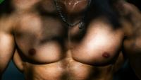 Le torse musclé d'un homme qui s'entraîne sur une aire de street workout à Paris, le 10 août 2025