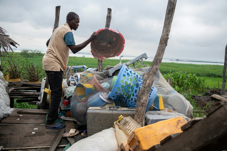 Un pêcheur jettent des déchets plastiques qu'il a ramassés en bateau près du fleuve Congo, sur l'île de Kimpoko, à Kinshasa, le 27 avril 2026 en RDC