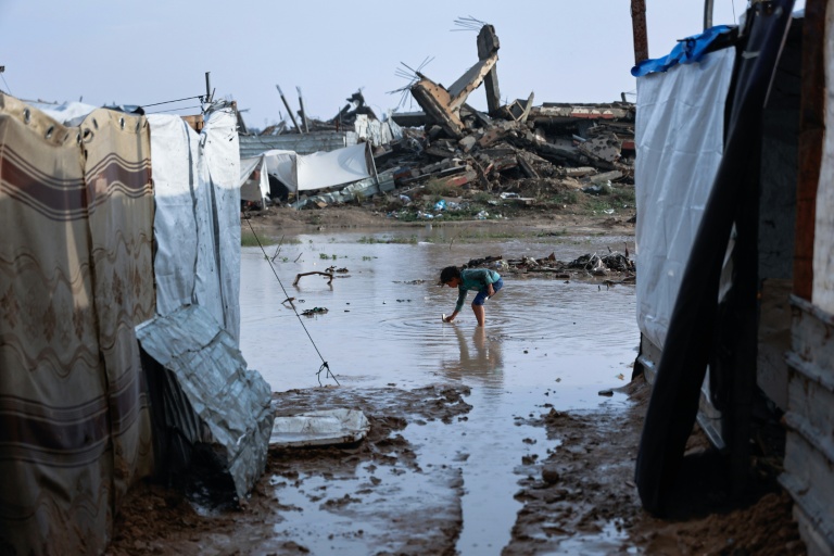 Une petite fille dans une mare d'eau, dans un camp de déplacés du quartier de Zeitoun, à Gaza-ville, inondé par la tempête Byron, le 11 décembre 2025