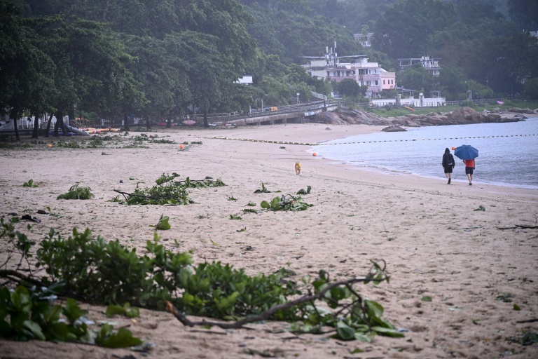 Des personnes se promènent sur une plage jonchée de débris laissés par le typhon Noul, à Hong Kong, le 26 juillet 2026
