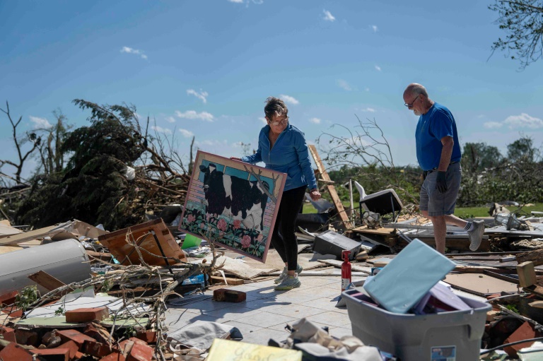 Un couple tente de récupérer quelques objets dans les ruines de leur maison après une tornade à London, dans le Kentucky, le 17 mai 2025