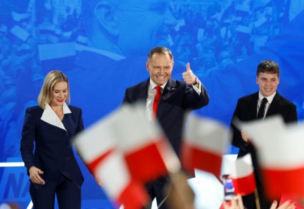 Karol Nawrocki, accompagné de son épouse Marta, salue ses partisans après l'annonce des sondages de sortie des urnes, lors du deuxième tour de la présidentielle, le 1er juin 2025 à Varsovie, en Pologne 