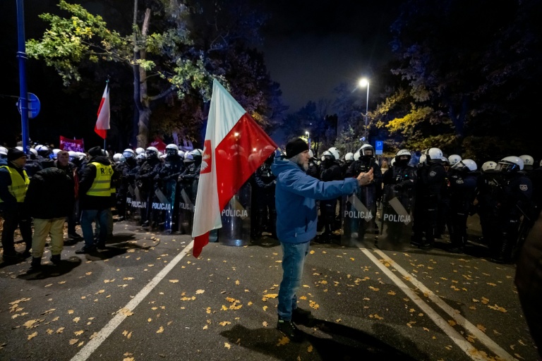 Un manifestant tient un drapeau polonais face à un cordon de policier près de la Cour constitutionnelle, le 30 octobre 2026 à Varsovie