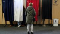 Une femme attend qu'un isoloir se libère pour voter au premier tour des élections municipales, le 15 mars 2026 au Touquet 