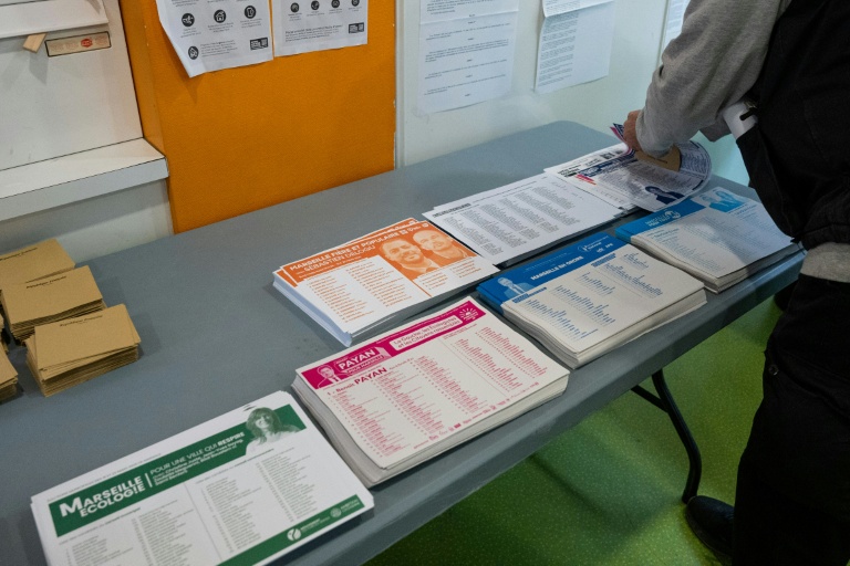 Un citoyen prend ses bulletins de vote dans un bureau de vote avant de se rendre à l'isoloir à Marseille le 15 mars 2026