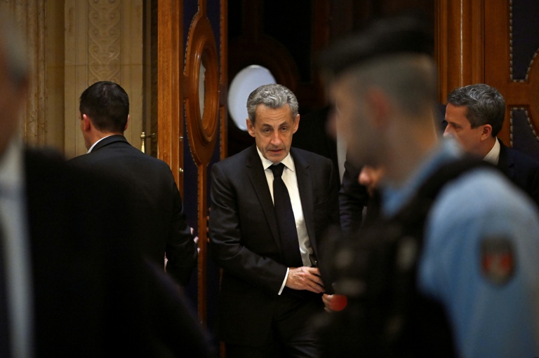 L'ancien président Nicolas Sarkozy (c) quitte le palais de justice de Paris pendant une pause dans le cadre de son procès en appel sur le financement libyen de sa campagne présidentielle de 2007, le 16 mars 2026