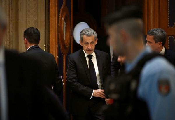 L'ancien président Nicolas Sarkozy (c) quitte le palais de justice de Paris pendant une pause dans le cadre de son procès en appel sur le financement libyen de sa campagne présidentielle de 2007, le 16 mars 2026