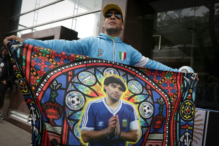Un fan tient un drapeau à l'effigie de la légende du football argentin Diego Maradona devant le tribunal à San Isidro, le 8 octobre 2026 en Argentine