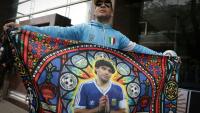 Un supporter tient un drapeau à l'effigie de Diego Maradona, avant une audience du procès sur le décès de la légende du football argentin, devant le tribunal à San Isidro, le 8 octobre 2026 en Argentine