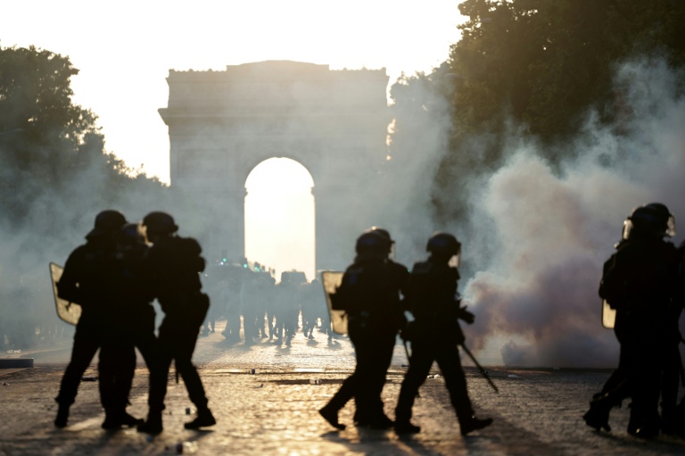Des membres des CRS au milieu des fumées de gaz lacrymogène sur l'avenue des Champs-Élysées, à Paris, lors de la finale de la Ligue des champions de l'UEFA opposant le Paris Saint-Germain (PSG) à Arsenal FC à Budapest, le 30 mai 2026
