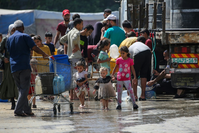 Des Palestiniens se rassemblent pour remplir leurs conteneurs d'eau à Nousseirat, dans le centre de la bande de Gaza, le 24 mai 2025