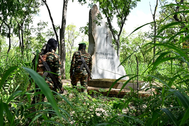 Des gardes forestiers devant la tombe de Raphaël Matta, tué par des braconniers en 1959, dans le parc national de la Comoé, le 10 octobre 2025 au nord-est de la Côte d'Ivoire