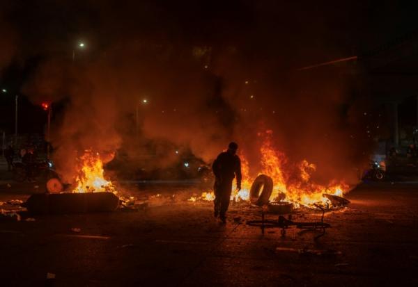 Un homme jette un pneu dans un feu lors d'affrontements avec la police, alors que des manifestants protestent contre les résultats préliminaires du second tour de l'élection présidentielle à Bogotá, en Colombie, le 21 juin 2026