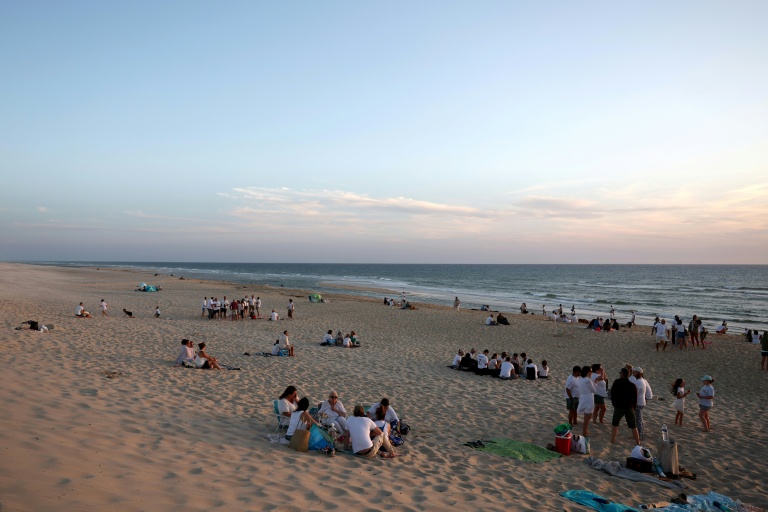Des personnes vêtues de blanc rassemblées sur la plage du Porge pour soutenir les commerces de la commune, le 7 août 2026, en Gironde