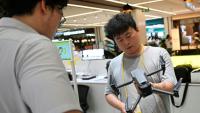 Un employé (à droite) d'un magasin dans un centre commercial inspecte un drone apporté par son propriétaire à Pékin le 16 septembre 2026.