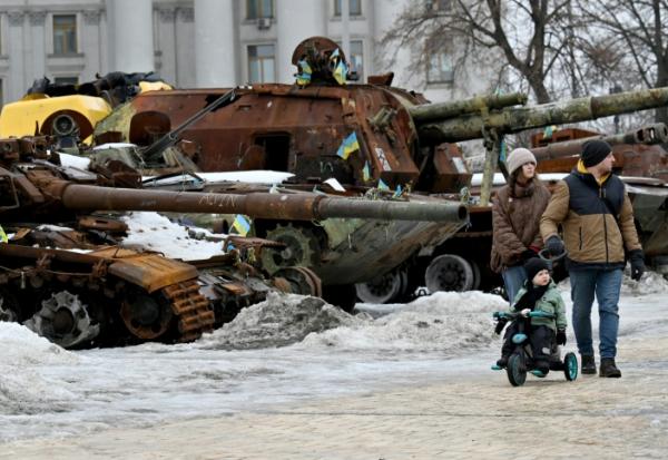 Un couple et un enfant à vélo se promènent dans l'exposition en plein air d'équipements militaires russes détruits à Kiev, le 15 février 2026