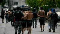 Des policiers escortent des criminels présumés arrêtés lors d'une opération dans la favela de Vila Cruzeiro, dans le complexe de Penha, à Rio de Janeiro, le 28 octobre 2025 au Brésil