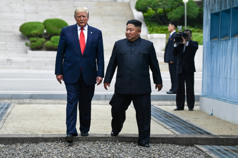 Le président américain Donald Trump (g.) et le dirigeant nord-coréen Kim Jong Un traversent ensemble la ligne de démarcation militaire qui sépare la Corée du Nord et la Corée du Sud, le 30 juin 2019 à Panmunjom en Corée du Sud