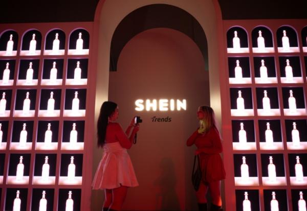 Des invités posent devant le logo Shein pendant le premier défilé italien de la plateforme, le 16 octobre à 2025 à Milan   