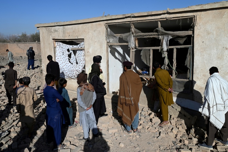 Des habitants devant une maison endommagée par un raid aérien pakistanais, en périphérie de Kaboul, le 13 mars 2026 en Afghanistan