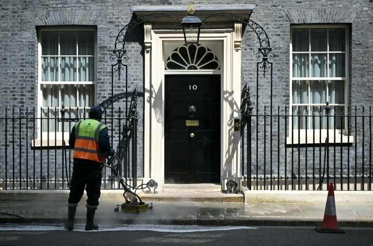 Des employés nettoient la rue devant l'entrée du 10 Downing Street, résidence officielle du Premier ministre britannique, le 9 mai 2026, à Londres