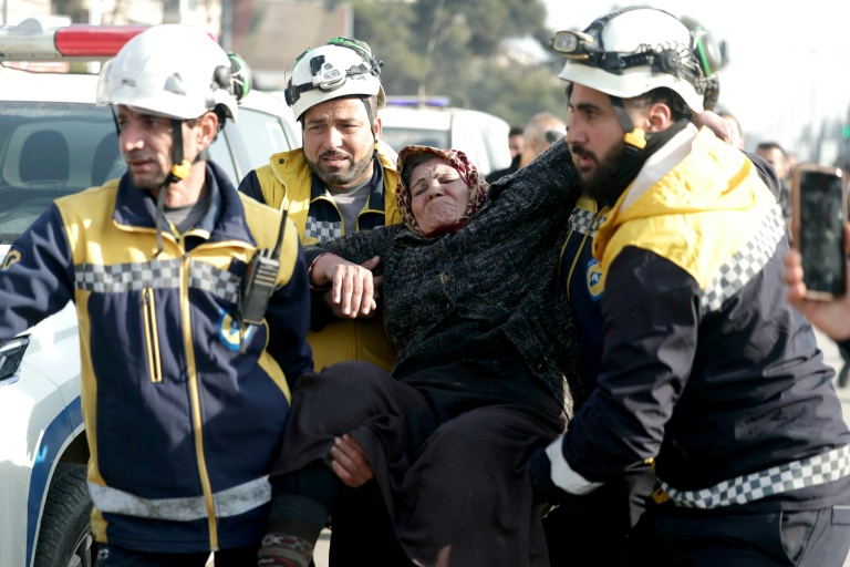 Des membres de la Défense civile syrienne aident une femme déplacée ayant fui les quartiers kurdes d'Alep, encerclés par l'armée, le 8 janvier 2026