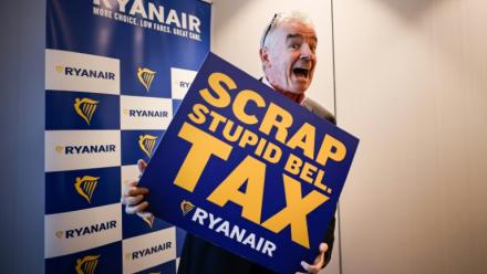Michael O'Leary, PDG de la compagnie aérienne Ryanair pose avec une pancarte reprochant à la Belgique une série de taxes "stupides", lors d'une conférence de presse à Bruxelles le 14 janvier 2026