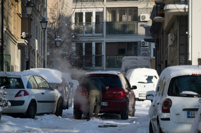 Un homme pousse une voiture immobilisée dans une rue enneigée de Belgrade, le 8 janvier 2026