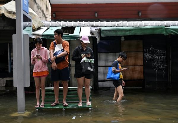 Des habitants sur un banc dans une rue de Bangkok, où l'état de catastrophe naturelle a été déclaré après des pluies diluviennes qui ont inondé habitations, commerces et axes de circulation, le 27 septembre 2026